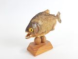 une sculpture en bois représentant un poisson, posée sur un socle en bois