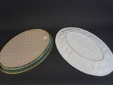 two white plates with green trims and a white lid on a black surface