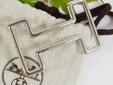 two metal hooks on top of a cloth bag with a leaf in the background