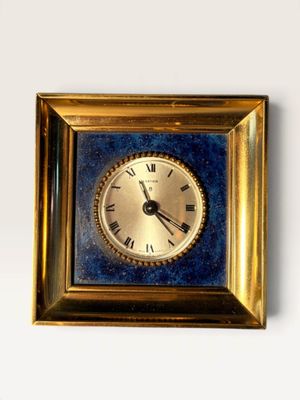 a gold clock with roman numerals in a gold frame