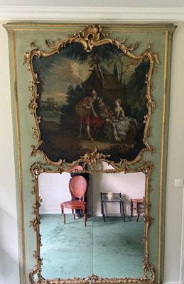 a large mirror with a painting on it in a room
