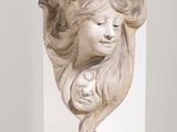 sculpture représentant la tête d'une femme, posée sur un socle blanc