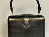 un sac à main noir avec une poignée dorée sur fond blanc