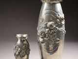 two silver vases sitting next to each other on a table