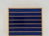 a close up of a blue and gold pin on a white wall