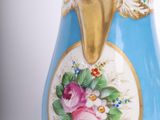 a blue vase with a gold handle and flowers on it