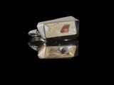 pair of silver and red stone cufflinks on a black surface
