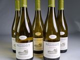four bottles of white wine are lined up on a table