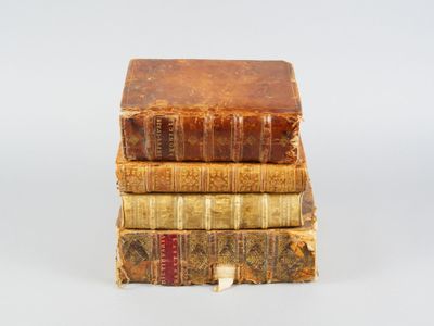 trois vieux livres empilés sur une surface blanche