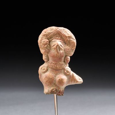 statue d'une femme coiffée d'un chapeau sur un piquet, devant un fond noir