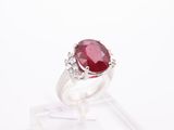 a close up of a ring with a red stone surrounded by diamonds
