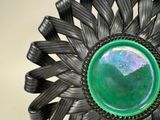 a green glass in the center of a black metal ring