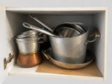 pots and pans are sitting on a shelf in a cabinet