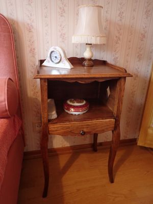 une petite table sur laquelle se trouve une horloge, à côté d'un lit
