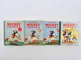 three mickey mouse books are lined up on a white surface