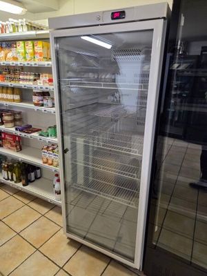 a refrigerator in the middle of a store with shelves full of food