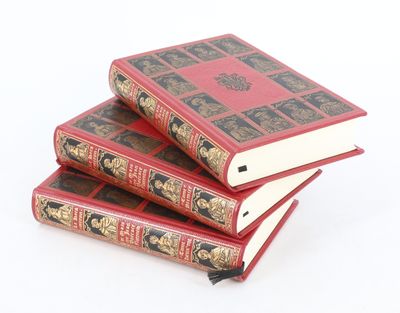 trois livres rouges empilés les uns sur les autres sur une surface blanche