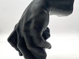 a black sculpture of a hand holding something in it ' s right hand