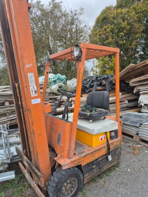 un chariot élévateur garé devant un tas de bois