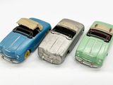 trois petites voitures disposées côte à côte sur une surface blanche