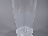 a clear glass vase with a circular base on a gray surface