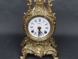 une horloge en or posée sur une table à côté d'une clé