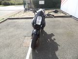a black motorcycle parked in a parking lot next to a fence