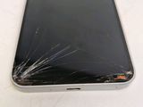 a broken cell phone sitting on a table with a broken screen