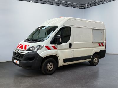 La camionnette blanche est garée à l'intérieur d'un bâtiment et présente une bande rouge sur le côté.