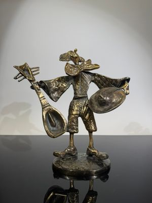 bronze figurine of a man playing a musical instrument on a black surface