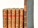 several old books are lined up in a row on a white surface