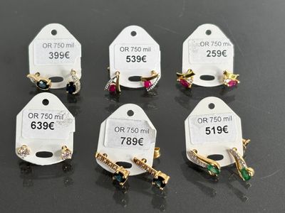 six pairs of earrings with price tags on them sitting on a table