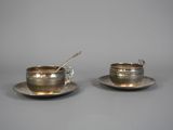 paire de tasses et soucoupes en métal argenté, avec des cuillères posées sur les soucoupes