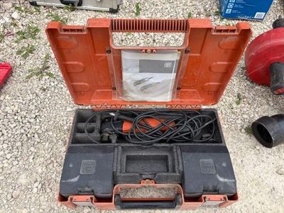 une boîte à outils contenant une perceuse et d'autres outils, posée par terre