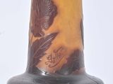 a brown vase with a flower on it on a white surface