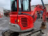 an image of a small red excavator parked in a parking lot