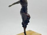 statue en bronze représentant une femme, posée sur un socle en bois, les bras tendus