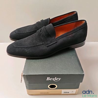 mocassins en daim noir pour homme, posés sur une boîte