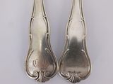pair of silverware spoons on a white surface with a white background