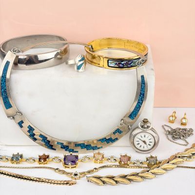 de nombreux bijoux posés sur une table blanche, sur fond rose