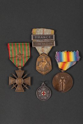 three medals and a cross are on a black surface