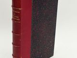 an old book with a red cover sitting on top of a white surface