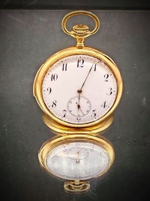 une montre de poche en or posée sur une table en verre
