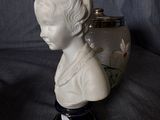porcelain bust of a woman with earrings and a vase on a table