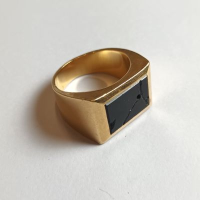 une photo d'une bague en or sertie d'une pierre noire