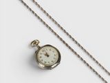 une montre de poche en argent, suspendue à une chaîne, posée sur une surface blanche