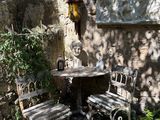a small table and two chairs in the shade of a tree