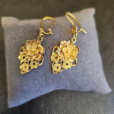 un gros plan sur une paire de boucles d'oreilles posées sur un oreiller