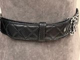 a close up of a woman wearing a black belt with silver buckles