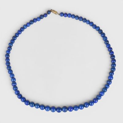 un gros plan d'un collier de perles bleues sur fond blanc